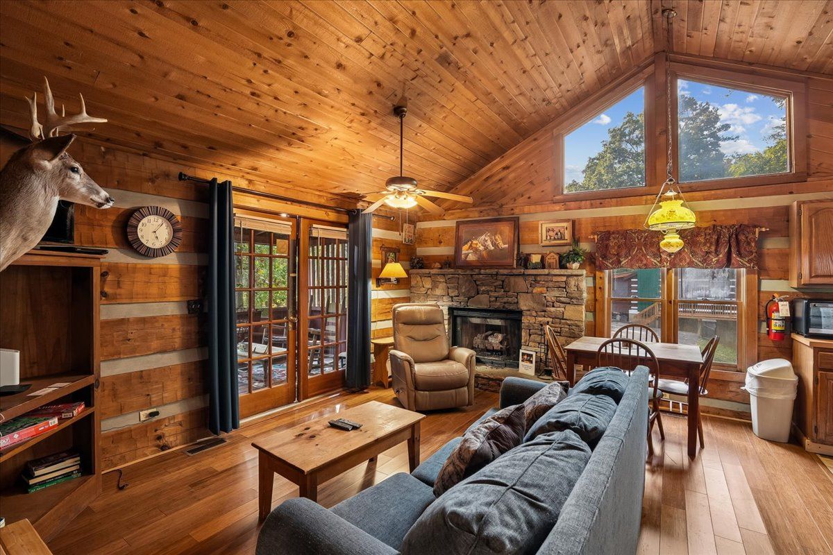 A log cabin interior with a fireplace, wooden furniture, and a deer head decoration.