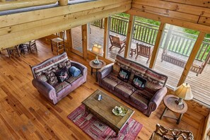 A wooden deck with outdoor furniture, a wooden ceiling, and a view of a green landscape.