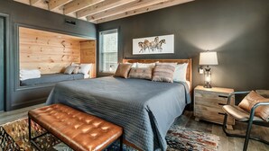 A bedroom with a large bed, a bench, a nightstand, and a chair.