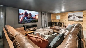 A modern living room with a leather sofa, a coffee table, and a TV displaying a movie scene.