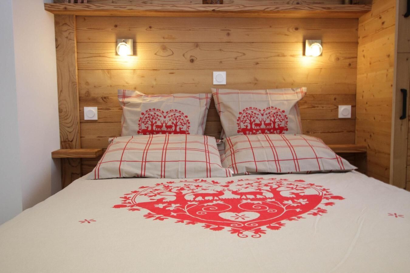 Una habitación tipo cabaña de madera con una cama y ropa de cama con estampado rojo y blanco.