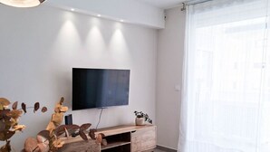 Ein modernes Wohnzimmer mit einem Holz-TV-Schrank, einem Flachbildfernseher, einem Glastisch und einem Sofa.