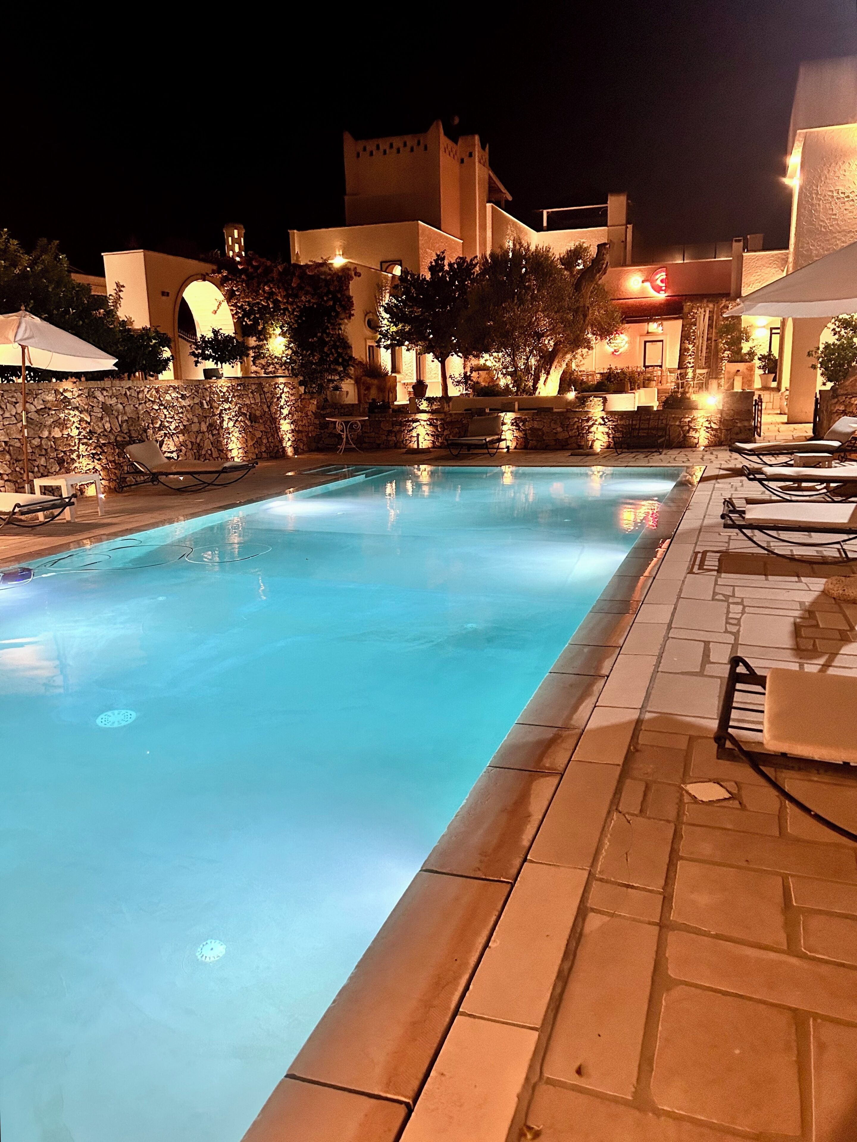 A swimming pool with lounge chairs and a stone wall.