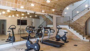 A gym with exercise equipment, a large mirror, and a staircase.