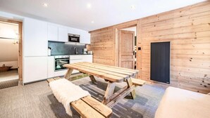 A modern kitchen with white cabinets, a wooden dining table, and benches. - 200m from ski lifts, Ground floor, terrace, parking, tv, 45m², Morzine (Morzine)
