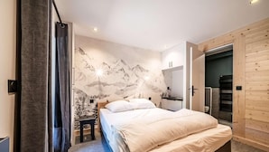 A bedroom with a bed, a nightstand, a desk, and a bathroom with a shower. - 200m from ski lifts, Ground floor, terrace, parking, tv, 45m², Morzine (Morzine)