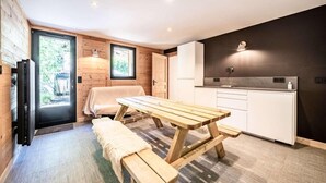 A compact kitchen with a wooden table and bench, a small window, and a dark wall. - 200m from ski lifts, Ground floor, terrace, parking, tv, 45m², Morzine (Morzine)