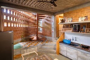 Una cocina con pared de ladrillo, una escalera en espiral y una encimera con un lavamanos y diversos utensilios de cocina.