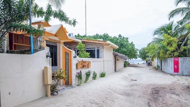 A residential area with a house featuring a balcony, a small garden, and a sandy driveway. - Moro Rasdhoo (Rasdhoo)