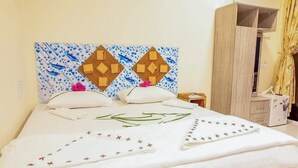 A neatly made bed with decorative pillows and a headboard with a geometric pattern. - Moro Rasdhoo (Rasdhoo)