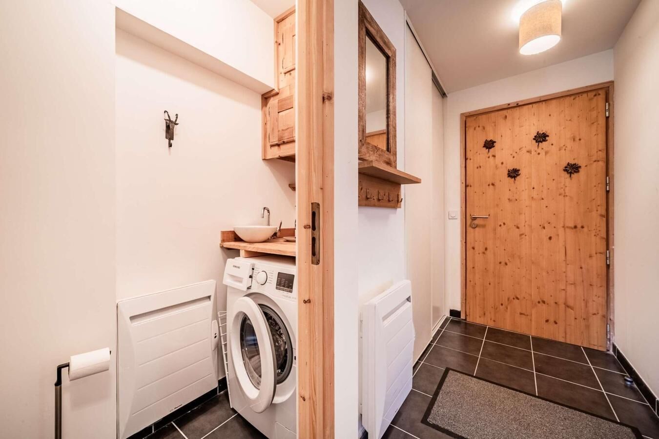 Ein Waschbereich mit Waschmaschine, Spüle und einer Holztür mit Verzierungen.