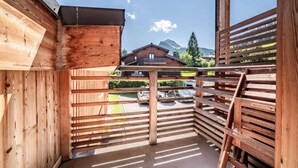 Ein Holzbalkon mit Blick auf einen Berg und ein geparktes Auto davor.