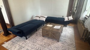 A room with a large bed, a wooden coffee table, and a patterned rug. - Red Roof Retreat - cozy home in Carson (Carson)