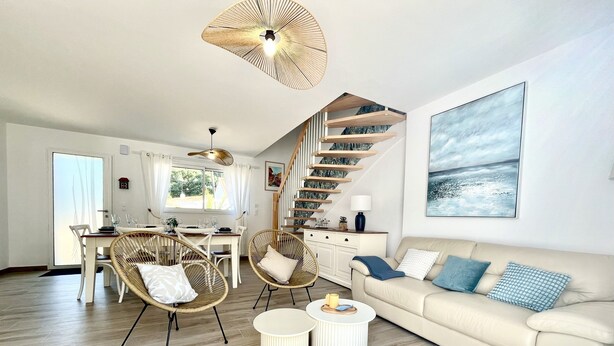 A modern living room with a sofa, two armchairs, a dining table, and a staircase. - Rincon del Mar - House with spa and hammocks, just 8 minutes from the sea (Saint-Hilaire-de-Riez)