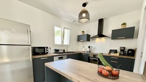 A modern kitchen with a stainless steel refrigerator, a microwave, a sink, and a wooden countertop. - Rincon del Mar - House with spa and hammocks, just 8 minutes from the sea (Saint-Hilaire-de-Riez)