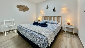 A bedroom with a bed, a white chair, a skylight, wall decor, and bedside lamps. - Rincon del Mar - House with spa and hammocks, just 8 minutes from the sea (Saint-Hilaire-de-Riez)