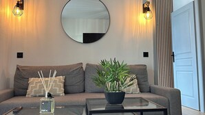 Uma sala de estar moderna com um sofá, uma mesa de centro, um espelho e iluminação embutida na parede.