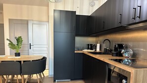 Uma cozinha moderna com armários pretos, forno de aço inoxidável e mesa de jantar de madeira com cadeiras.