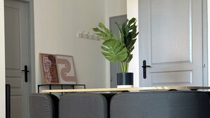 Uma área de refeições com uma mesa de madeira, quatro cadeiras estofadas cinzentas e um vaso com planta.