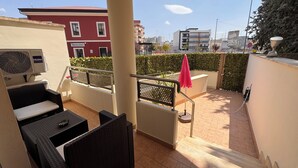 Un balcón con mobiliario de mimbre, un aire acondicionado Haier y vistas a la ciudad.
