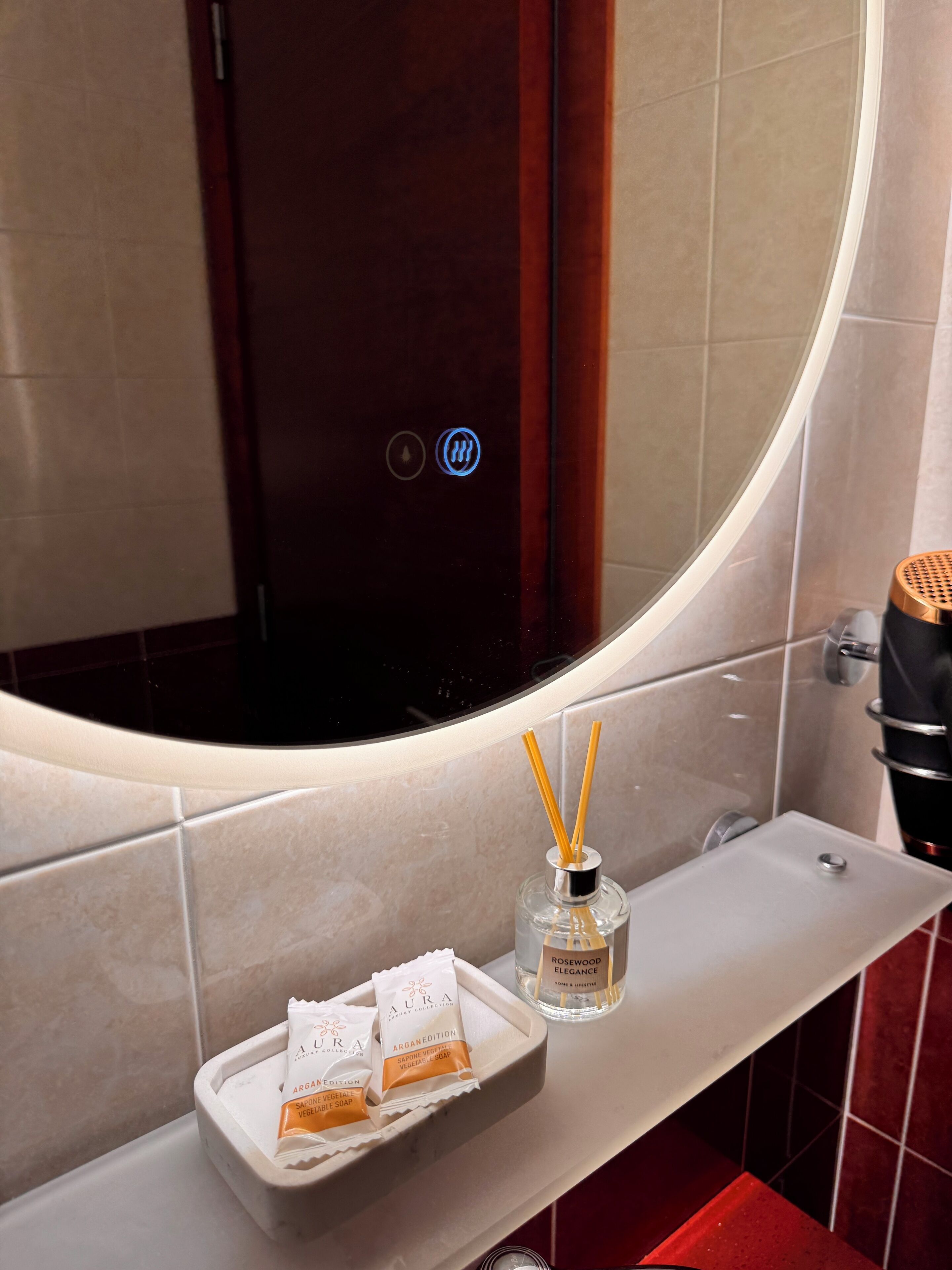Een badkamer met een wit wastafelmeubel, een spiegel en een schaal met zeepzakjes.