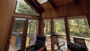A cozy room with wooden walls, large windows, and a skylight. - 3-bedroom mountain oasis in Black Butte Ranch surrounded by trees (Sisters)