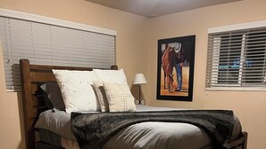 Ein Schlafzimmer mit einem hölzernen Bett, beigen Wänden und einem Teppichboden.