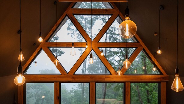 Une pièce dotée de grandes fenêtres, de poutres en bois, de luminaires suspendus et d’une cheminée.