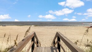 A wooden boardwalk leading to a sandy beach with a clear sky and ocean in the background. - Carolina Skies - Rooftop Deck - Ocean Views (Carolina Beach)