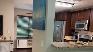 Una cocina con armarios de madera, un refrigerador de acero inoxidable, un microondas y una estufa.