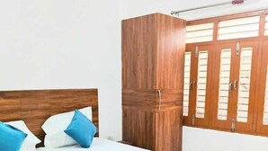 A bedroom with a wooden bed, a wardrobe, and a window with blinds. - Parvati Home Stay (Varanasi)
