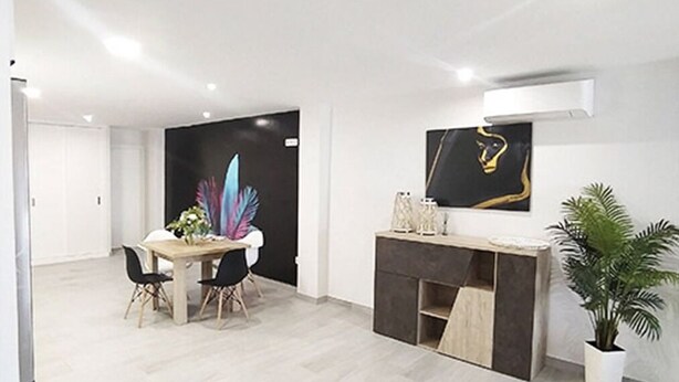 Un espace de vie moderne, à aire ouverte, comprenant un coin repas, un comptoir de cuisine et une plante en pot.