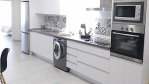Une cuisine moderne équipée d’un lave-linge, d’un four à micro-ondes et d’un four traditionnel.