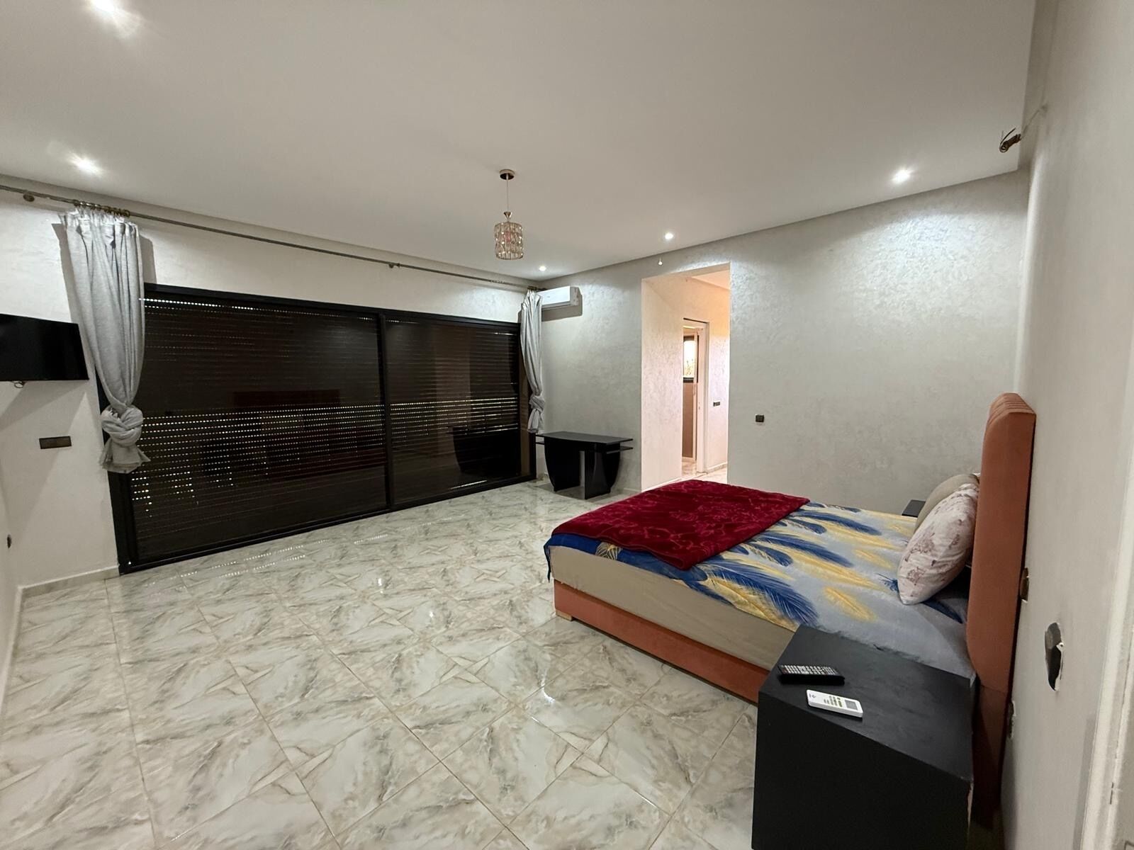 A bedroom with a bed, a desk, and a sliding door.