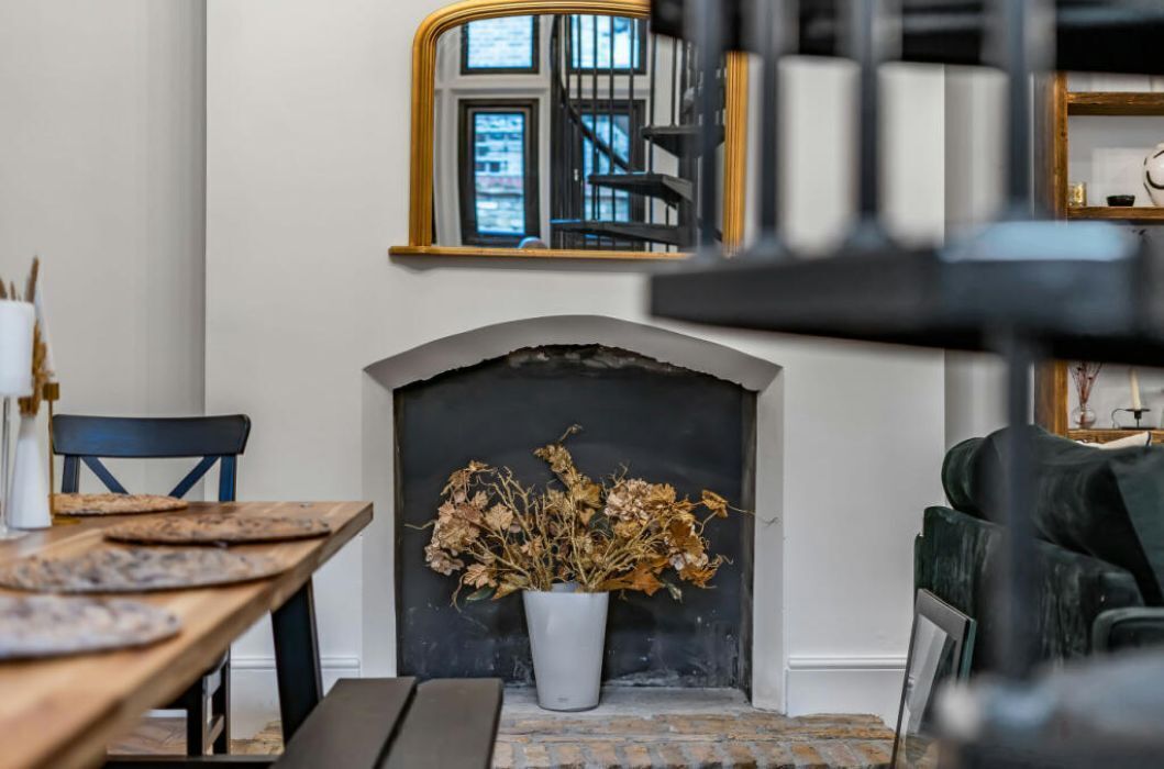Un coin repas avec une cheminée, un miroir et un escalier en arrière-plan.