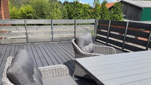 A deck with wicker furniture, including a sofa and a table. - Tillmanns Stadtlounge Exclusive 5 star vacation apartment in Norden. (Norden)