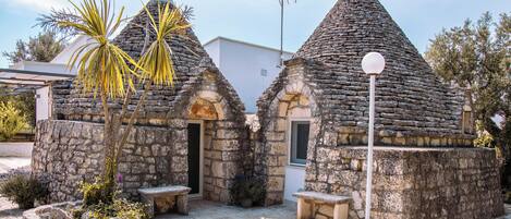 Un bâtiment en pierre doté d’un toit conique, d’une petite porte et d’un banc.