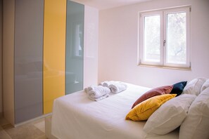 A bedroom with a bed, white towels, a window, and a wardrobe with a mirror. - Castellinaria Holiday (Castellana Grotte)