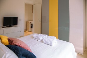 A hotel room with a bed, a TV, a washing machine, and a wardrobe.