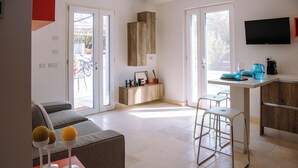 Een moderne keuken met een inbouwoven, een eethoek met barstoelen, en een bank in de woonkamer.