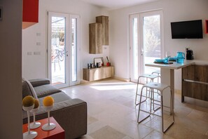 Eine moderne Küche mit Einbauofen, ein Essbereich mit Barhocker und ein Sofa im Wohnzimmer.