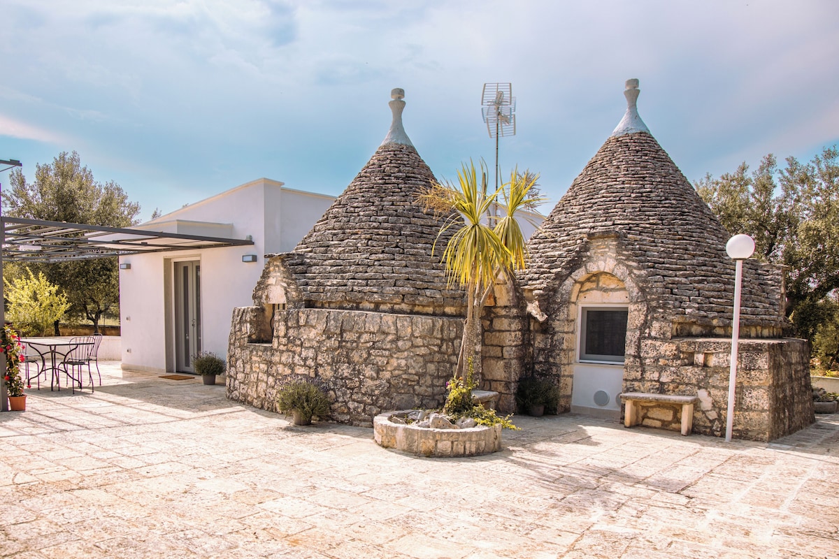 A stone building with conical roofs, a door, and a bench.