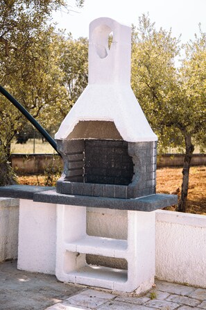 A stone-built outdoor oven with a chimney, surrounded by a low white wall and a metal fence. - Castellinaria Holiday (Castellana Grotte)
