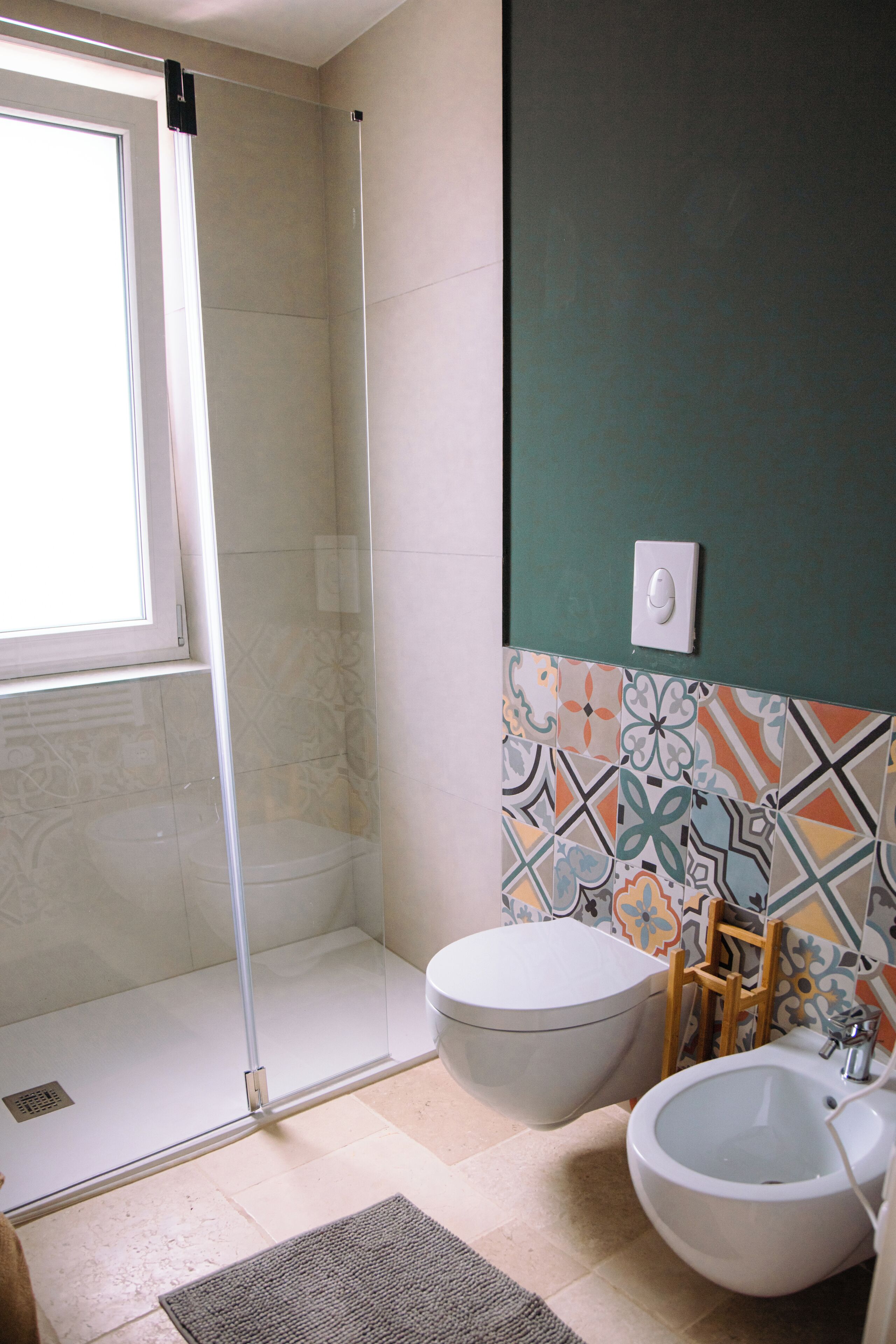 Et badeværelse med glasbrusekabine, toilet, bidet og vask.