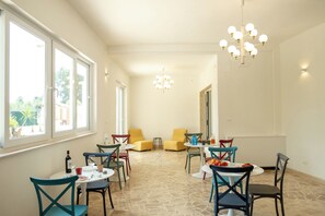 Un comedor con mesas redondas y cuadradas, sillas y una araña.