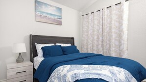 Un dormitorio con una cama, una mesita de noche con lámpara y un cuadro en la pared.