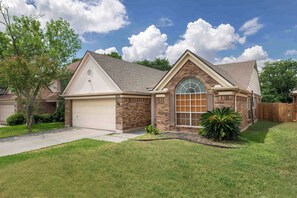 A single-story house with a garage, a brick facade, and a large arched window.