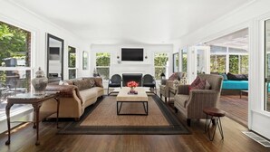 Amplia sala de estar con chimenea, asientos cómodos y grandes ventanales que ofrecen vistas al exterior.