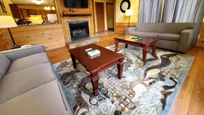 A cozy living room with a fireplace, a sofa, a coffee table, and a patterned rug.
