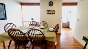 Un coin repas avec une table dressée pour quatre personnes, des chaises en bois et un panneau indiquant « Famille » sur le mur.